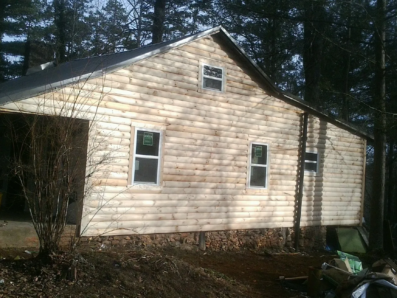 New log siding and dark metal roofing on a gable end in Texhoma
