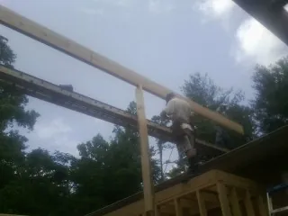 Carpenter setting a ridge beam over a new addition frame — Ice Dam Removal by Roofing Brothers in Texhoma