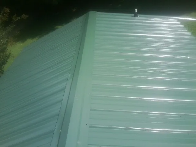 New green metal panels meeting at the ridge of a roof — Flat Roof Repair work by our crew in Texhoma