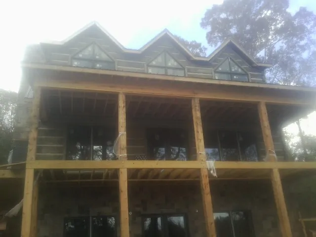 Dormers and porch framing on a large log home under construction — Roof Coating work by our crew in Texhoma