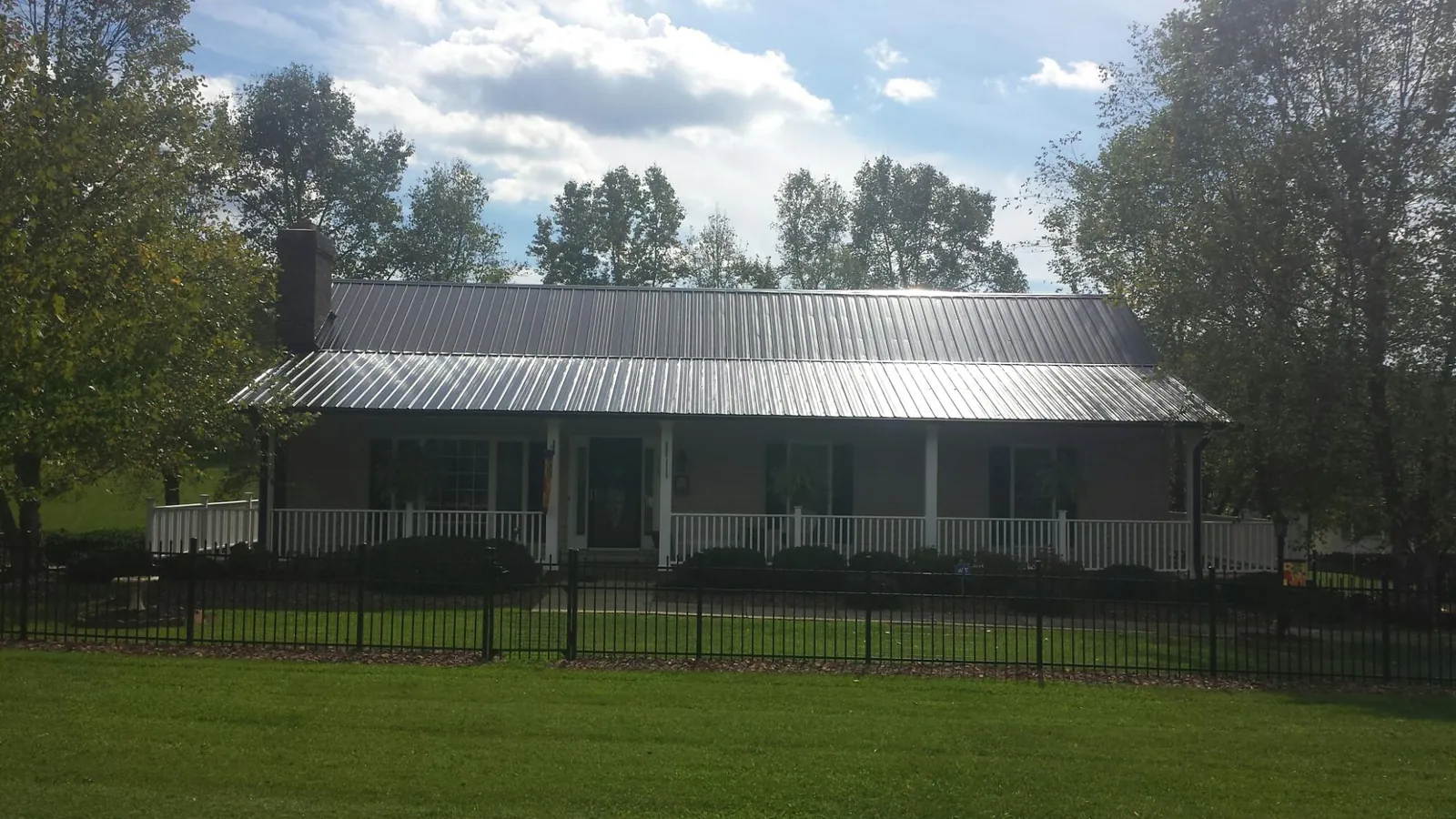 Gray metal roof on a brick ranch with a full width front porch — Gutter Guard Installation work by our crew in Texhoma