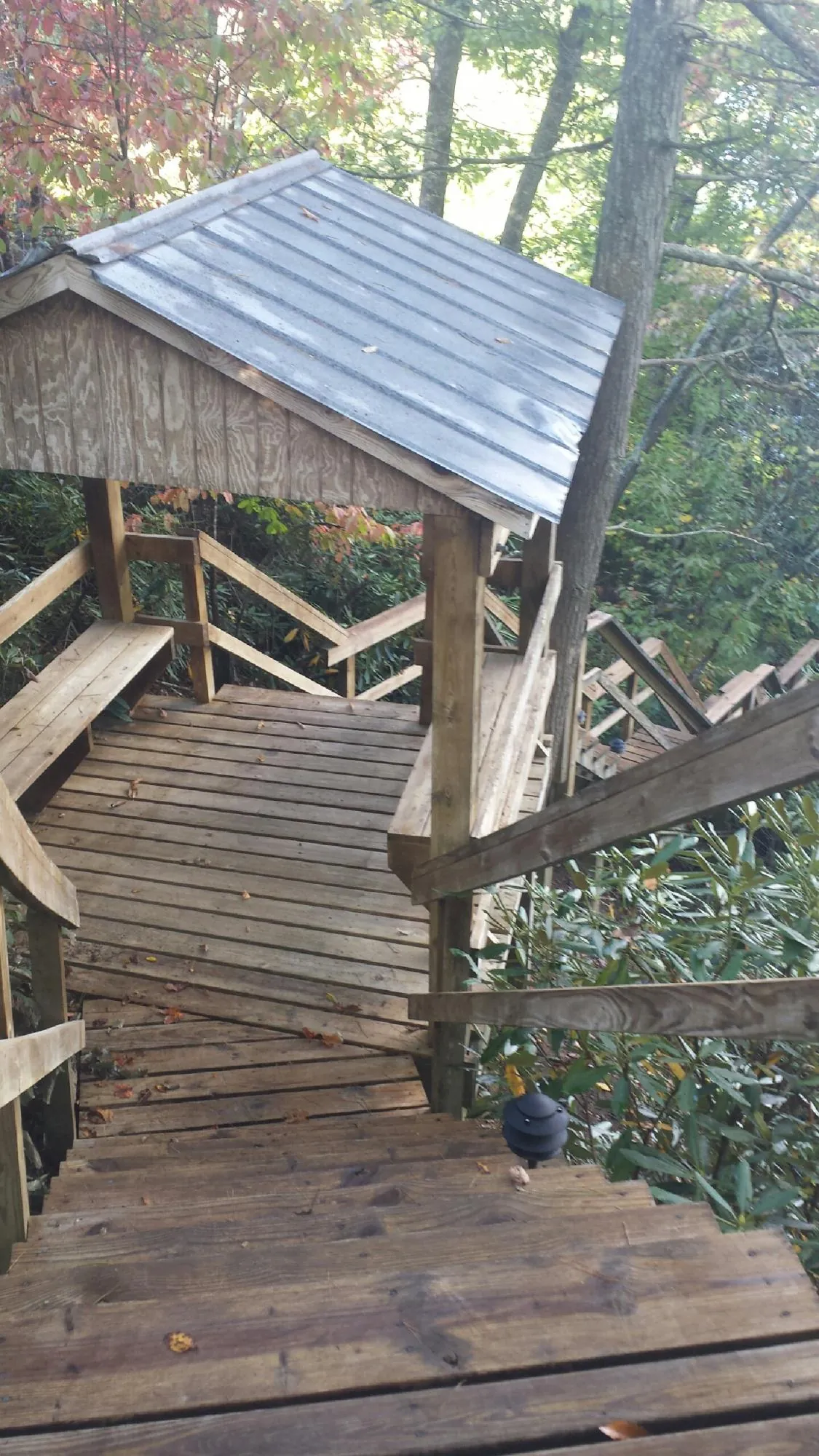 Metal roofed shelter over wooden steps on a wooded walkway — Skylight Repair & Installation work by our crew in Texhoma