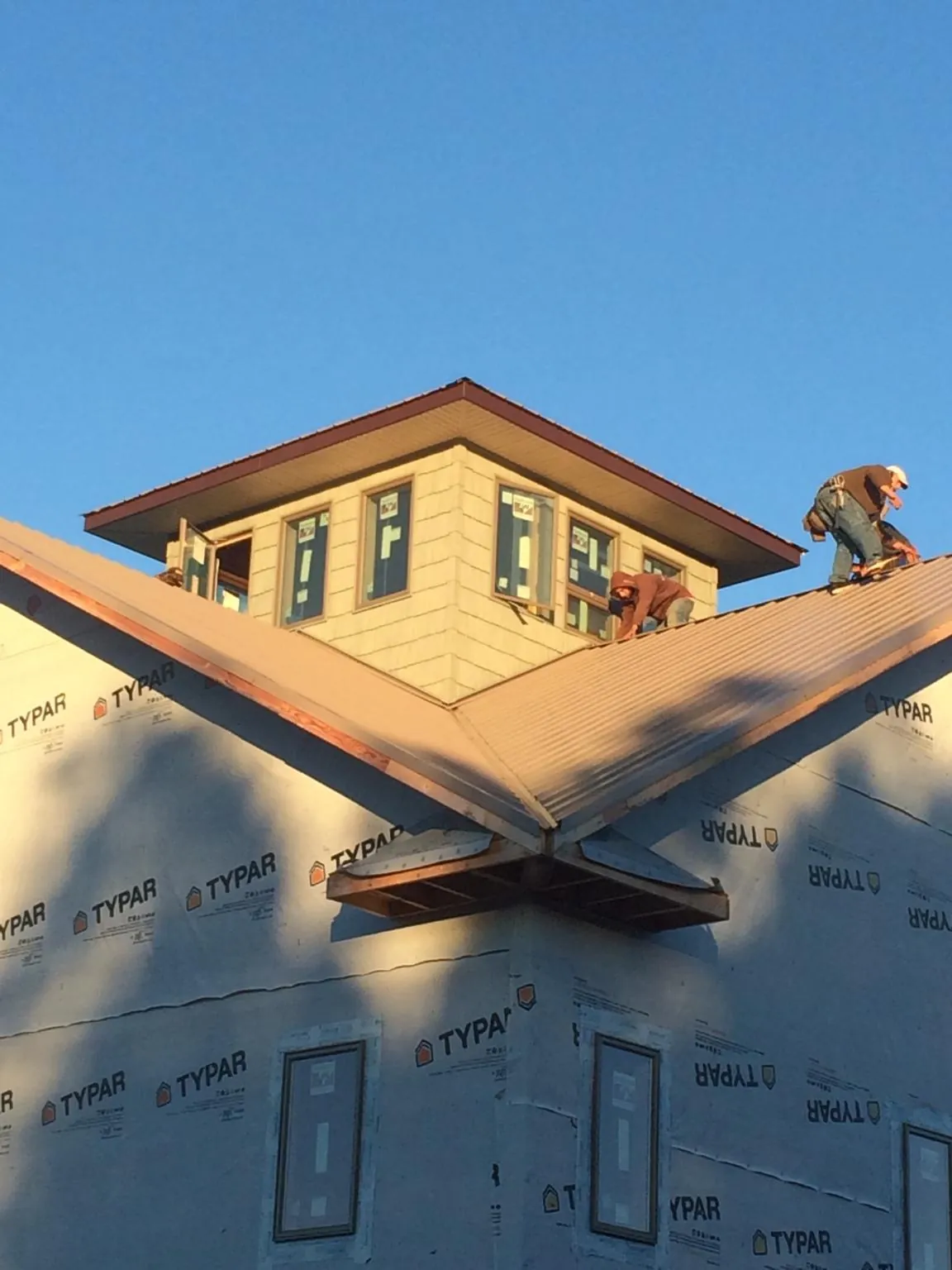 Roofers working around a rooftop cupola on a new metal roof at sunset — Roof Waterproofing in Texhoma by Roofing Brothers
